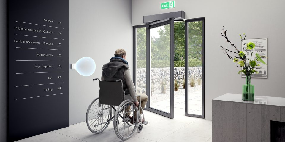 Eine Person im Rollstuhl mit eingeschränkter Mobilität profitiert von einem berührungslosen Taster